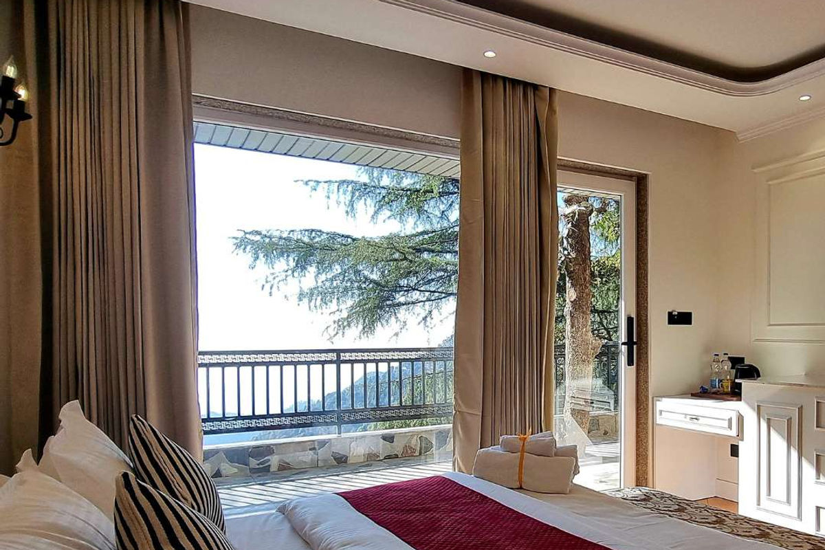 Executive Room at Akasa Dalhousie — king bed with open balcony door and pine tree mountain valley views